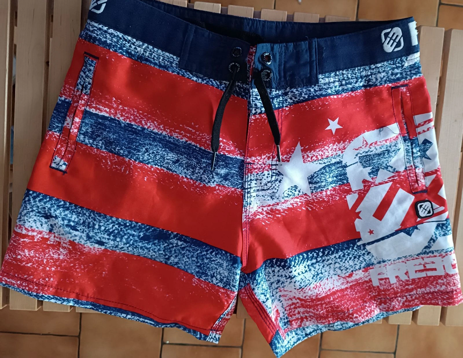 Boardshort / Short de bain Freegun rouge, bleu
et blanc motif étoiles XS
